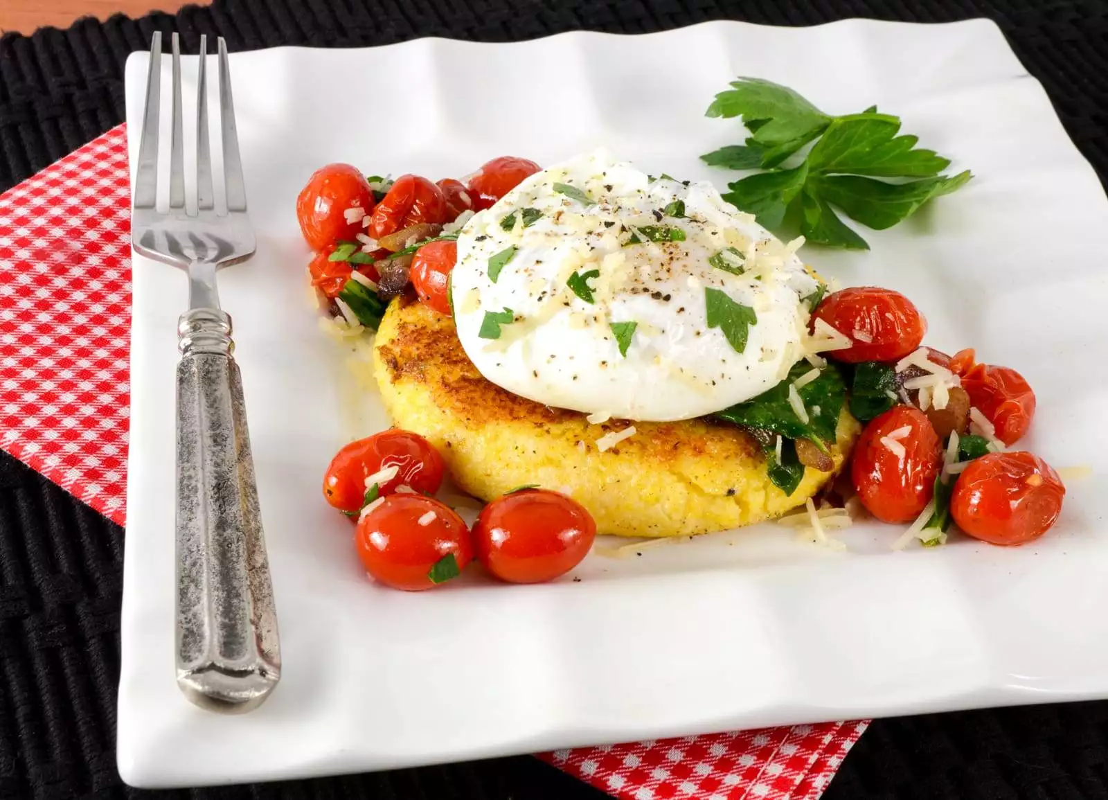 Polenta Cake Topped with Sautéed Tomatoes, Spinach, and a Poached Egg