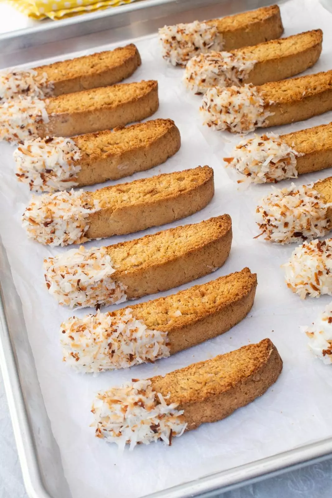 Crunchy, buttery, and full of coconut flavor, these white chocolate dipped toasted coconut biscotti are irresistible.  My whole family loves biscotti and coconut so I finally combined the two and made these deliciously crunchy toasted coconut biscotti. They were fun to make, smelled terrific while baking, and made my entire family happy. Dipping these tasty toasted coconut biscotti in coffee or tea makes them extra special. Toasted Coconut Biscotti Biscotti Ingredients: 1/2 cup unsalted butter, softened to room temperature 1/2 cup brown sugar, packed 1/2 cup white sugar 2 large eggs, room temperature 2 tsp coconut extract 3/4 tsp vanilla extract 2 1/4 cups flour 1 1/4 tsp baking powder 1/2 tsp kosher salt 1/2 cup sweetened shredded coconut Other Ingredients: 1/2 cup sweetened shredded coconut, toasted 6 oz white chocolate melting wafers 1/4 tsp coconut oil How to Make Toasted Coconut Biscotti Preheat the oven to 350 degrees. Line a baking sheet with parchment paper. Make the biscotti by using a hand mixer to beat the butter, brown sugar, and white sugar together until creamy. Beat in the eggs, one at a time, along with the coconut extract and vanilla extract until creamy and smooth. Whisk the flour, baking powder, and salt together in a small bowl. Gradually add the flour mixture to the egg mixture until just combined. Add the shredded coconut and mix until combined. Divide the dough equally in two and place each half on the baking sheet. Shape each half into an 8-9-inch long slab about 1/2-inch thick. Side Note: The dough will be sticky. Bake the biscotti for 20 minutes, or until the top and sides of the biscotti slabs are lightly browned. Remove from the oven, but do not turn off the heat.  Allow the slabs to cool for 10 minutes. Once they have cooled enough to handle, cut each slab into 1-inch wide slices then carefully place the slices back on the baking sheet cut sides upright, 1/4-inch apart. Return to the oven to bake for 8 minutes. Carefully turn the biscotti over and continue to bake for 8 minutes. The cookies will be slightly soft in the centers and harder on the edges. Side Note: They will get crunchier as they cool. Toast the coconut by placing the remaining 1/2 cup of coconut in a dry large skillet over low heat. Cook, stirring often, for 4-5 minutes, or until the coconut is golden brown and toasted. Remove from the stovetop and set aside to cool. Prepare the dipping chocolate by placing the white chocolate wafers in a glass bowl with 1/4 teaspoon of coconut oil then put into the microwave for 30 seconds. Remove and stir then place back into the microwave for 15 seconds. Remove and stir then place back into the microwave for 10 seconds. Remove and stir until completely melted. If needed, continue cooking for 10-second increments. Be careful not to overcook the white chocolate! Dip the biscotti by dipping one end of each biscotti into the melted white chocolate then immediately sprinkle the top with the toasted coconut before the white chocolate dries. Place them on a parchment-lined baking sheet. Allow them to dry completely. Store in an airtight container at room temperature for up to 2 weeks. Enjoy!   WP Recipe Maker #74759 remove Toasted Coconut Biscotti Course: Breakfast, Dessert Cuisine: Italian Prep Time: 20m Cook Time: 45m Total Time: 65m Servings: 20 biscotti +/- Author: Pam - For the Love of Cooking - Baking Sheet - Hand mixer Biscotti Ingredients: - 1/2 cup unsalted butter softened to room temperature - 1/2 cup brown sugar packed - 1/2 cup white sugar - 2 large eggs room temperature - 2 tsp coconut extract - 3/4 tsp vanilla extract - 2 1/4 cups flour - 1 1/4 tsp baking powder - 1/2 tsp kosher salt - 1/2 cup sweetened shredded coconut Other Ingredients: - 1/2 cup sweetened shredded coconut toasted - 6 oz white chocolate melting wafers - 1/4 tsp coconut oil 1) Preheat the oven to 350 degrees. Line a baking sheet with parchment paper. 2) Make the biscotti by using a hand mixer to beat the butter, brown sugar, and white sugar together until creamy. Beat in the eggs, one at a time, along with the coconut extract and vanilla extract until creamy and smooth. 3) Whisk the flour, baking powder, and salt together in a small bowl. 4) Gradually add the flour mixture to the egg mixture until just combined. 5) Add the shredded coconut and mix until combined. 6) Divide the dough equally in two and place each half on the baking sheet. Shape each half into an 8-9-inch long slab about 1/2-inch thick. Side Note: The dough will be sticky. 7) Bake the biscotti for 20 minutes, or until the top and sides of the biscotti slabs are lightly browned. Remove from the oven, but do not turn off the heat.  Allow the slabs to cool for 10 minutes. 8) Once they have cooled enough to handle, cut each slab into 1-inch wide slices then carefully place the slices back on the baking sheet cut sides upright, 1/4-inch apart. 9) Return to the oven to bake for 8 minutes. 10) Carefully turn the biscotti over and continue to bake for 8 minutes. The cookies will be slightly soft in the centers and harder on the edges. Side Note: They will get crunchier as they cool. 11) Toast the coconut by placing the remaining 1/2 cup of coconut in a dry large skillet over low heat. Cook, stirring often, for 4-5 minutes, or until the coconut is golden brown and toasted. Remove from the stovetop and set aside to cool. 12) Prepare the dipping chocolate by placing the white chocolate wafers in a glass bowl with 1/4 teaspoon of coconut oil then put into the microwave for 30 seconds. Remove and stir then place back into the microwave for 15 seconds. Remove and stir then place back into the microwave for 10 seconds. Remove and stir until completely melted. If needed, continue cooking for 10-second increments. Be careful not to overcook the white chocolate! 13) Dip the biscotti by dipping one end of each biscotti into the melted white chocolate then immediately sprinkle the top with the toasted coconut before the white chocolate dries. 14) Place them on a parchment-lined baking sheet. 15) Allow them to dry completely. Store in an airtight container at room temperature for up to 2 weeks. Enjoy!     Toasted Coconut Biscotti